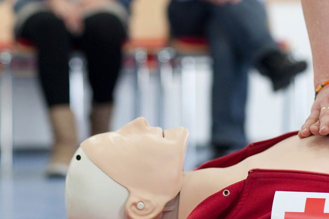 Foto: Eine DRK-Ausbilderin führt den Teilnehmern die Herzdruckmassage an einem Dummy vor.