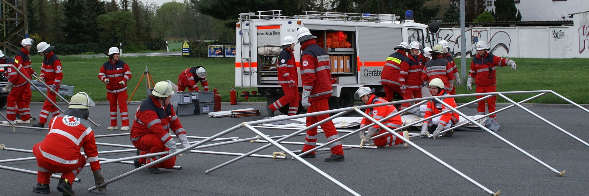 Foto: Zwei Mitarbeiter des DRK-Sanitätsdienstes tauschen sich am Spielfeldrand fachlich miteinander aus. Der Sanitätsrucksack liegt geöffnet zwischen den beiden.