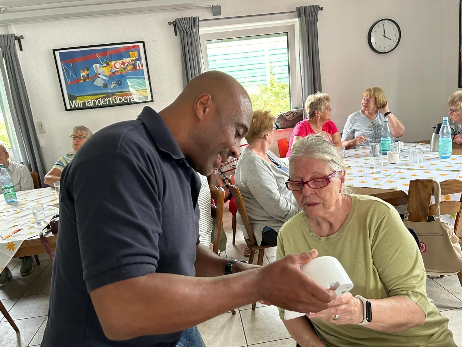HNR-Teamleiter Maurice Sports erläutert einer Seniorin die Funktionsweise des Hausnotrufgerätes