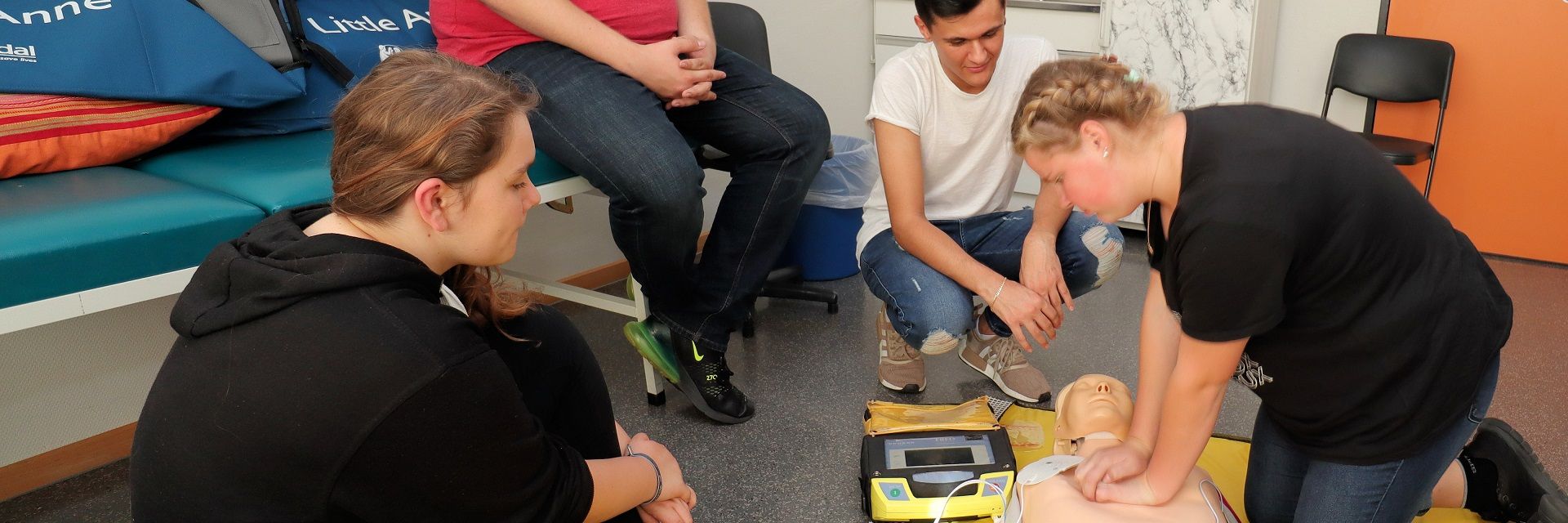 Foto: Eine DRK-Ausbilderin führt den Teilnehmern die Herzdruckmassage an einem Dummy vor.